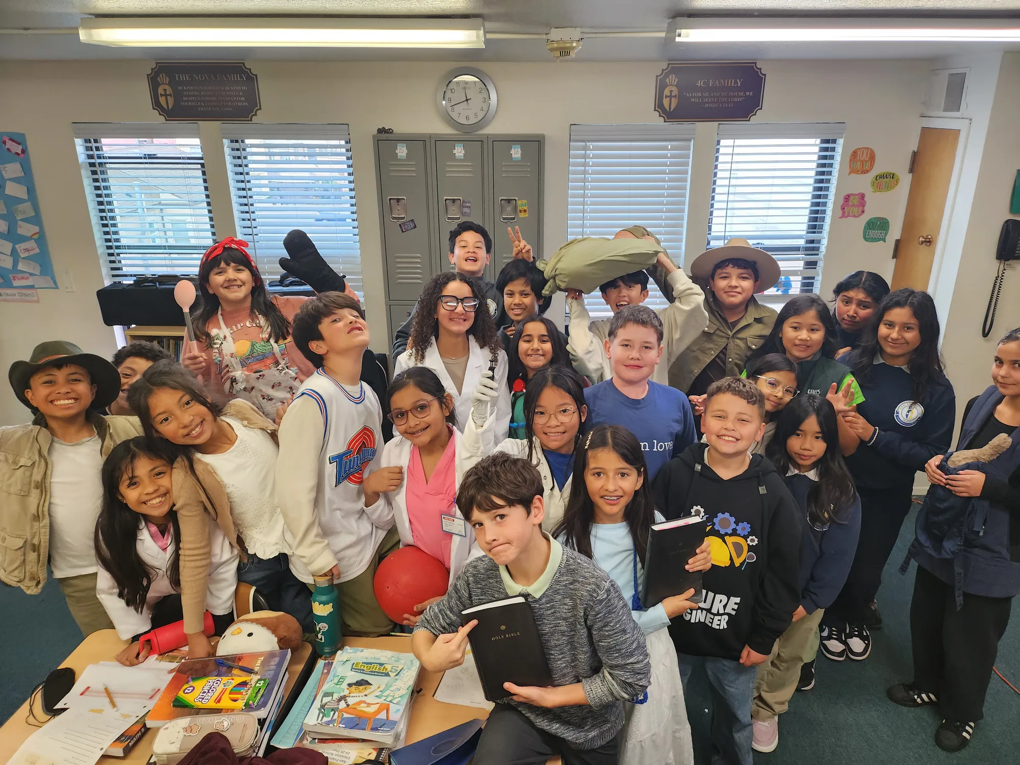 A student holding up a Bible during a class dress-up day, classmates smiling around him