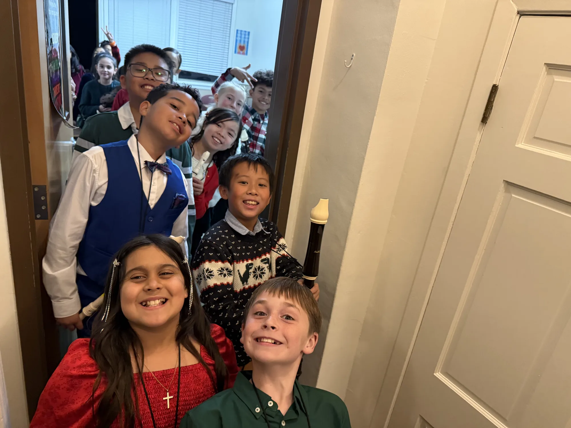 Students beaming backstage at the Christmas program, recorder in hand