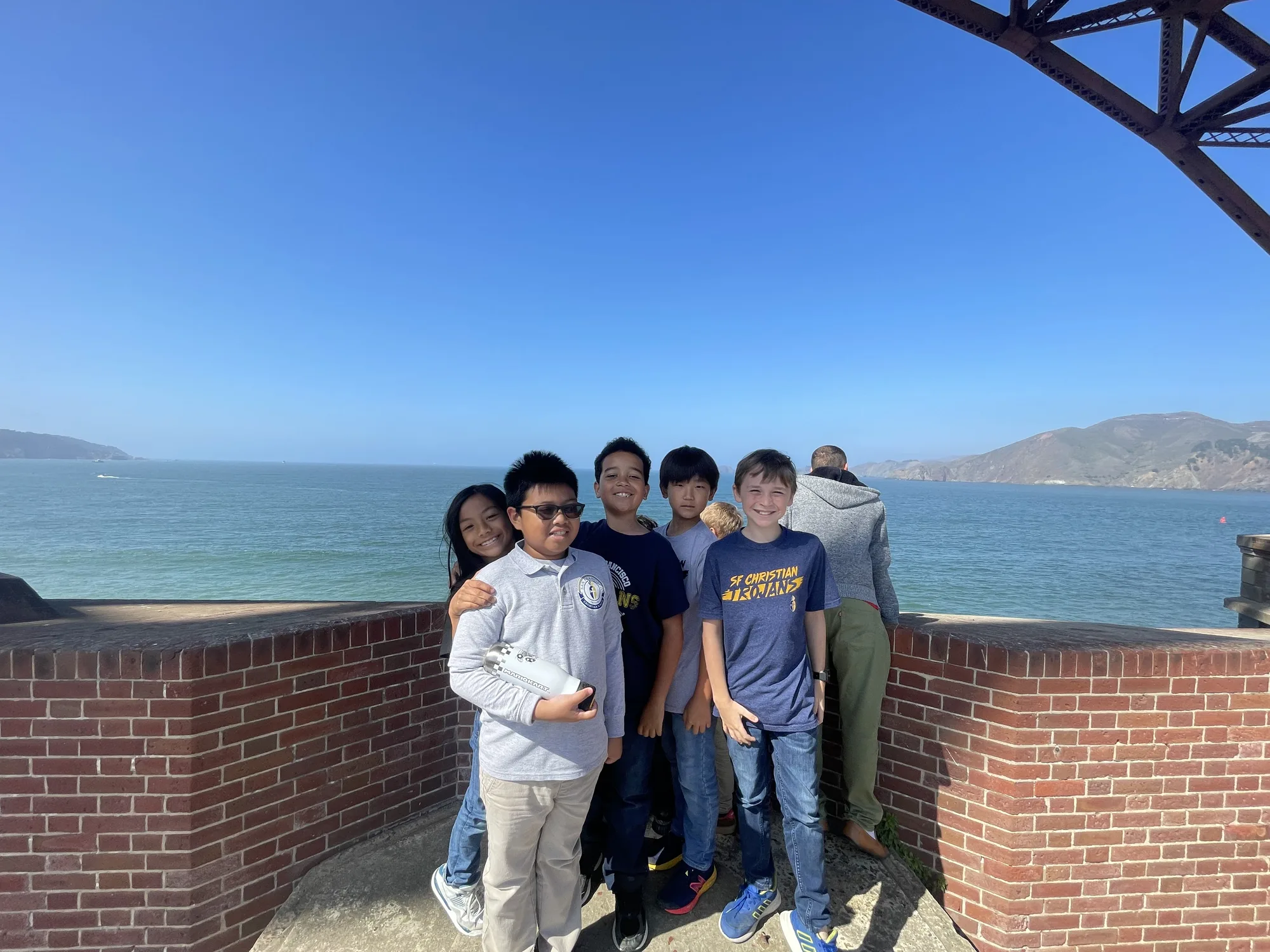 Five students at the bay wall at Fort Point with the ocean and Marin Headlands behind