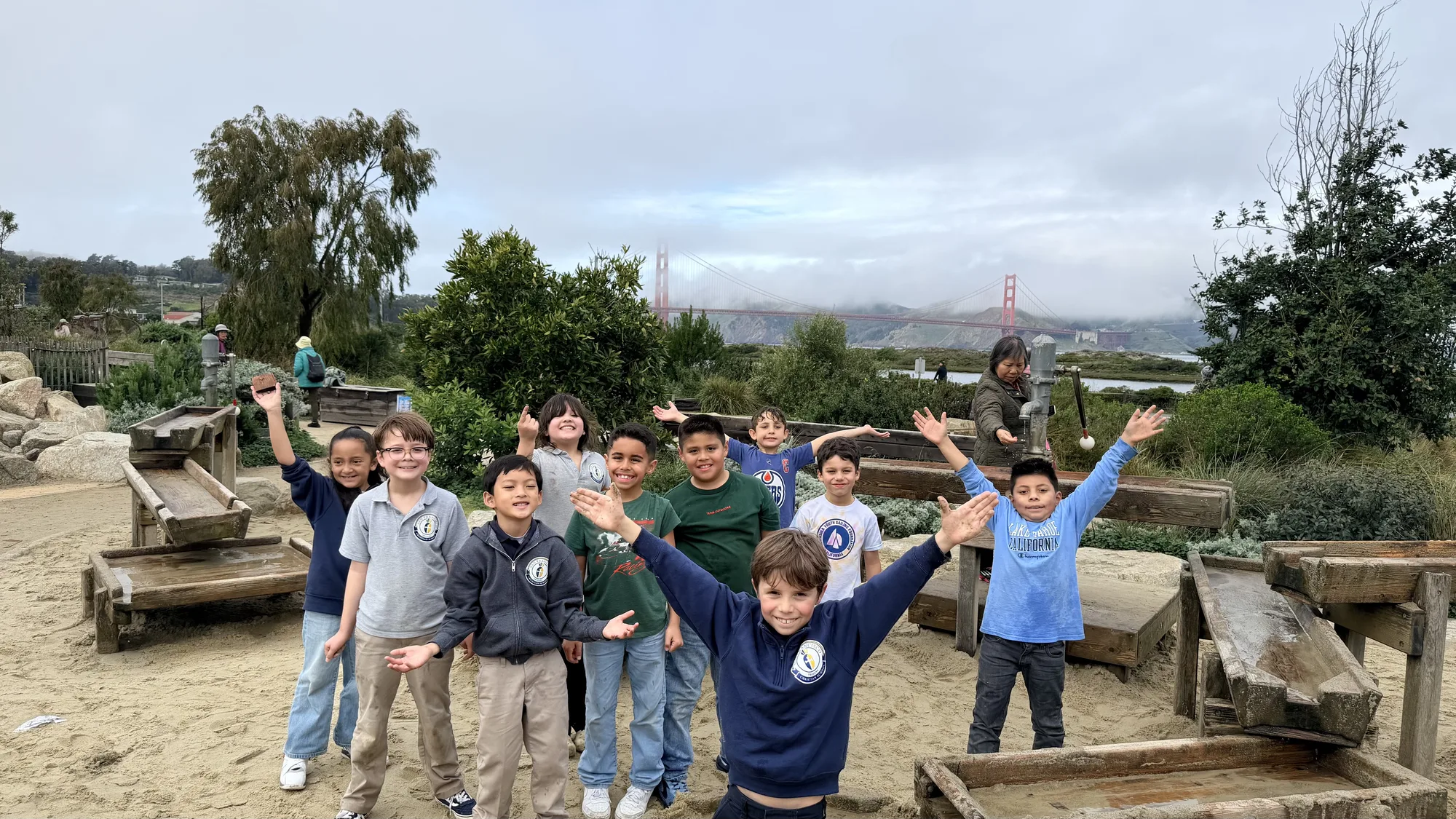 A class cheering together beneath the Golden Gate Bridge