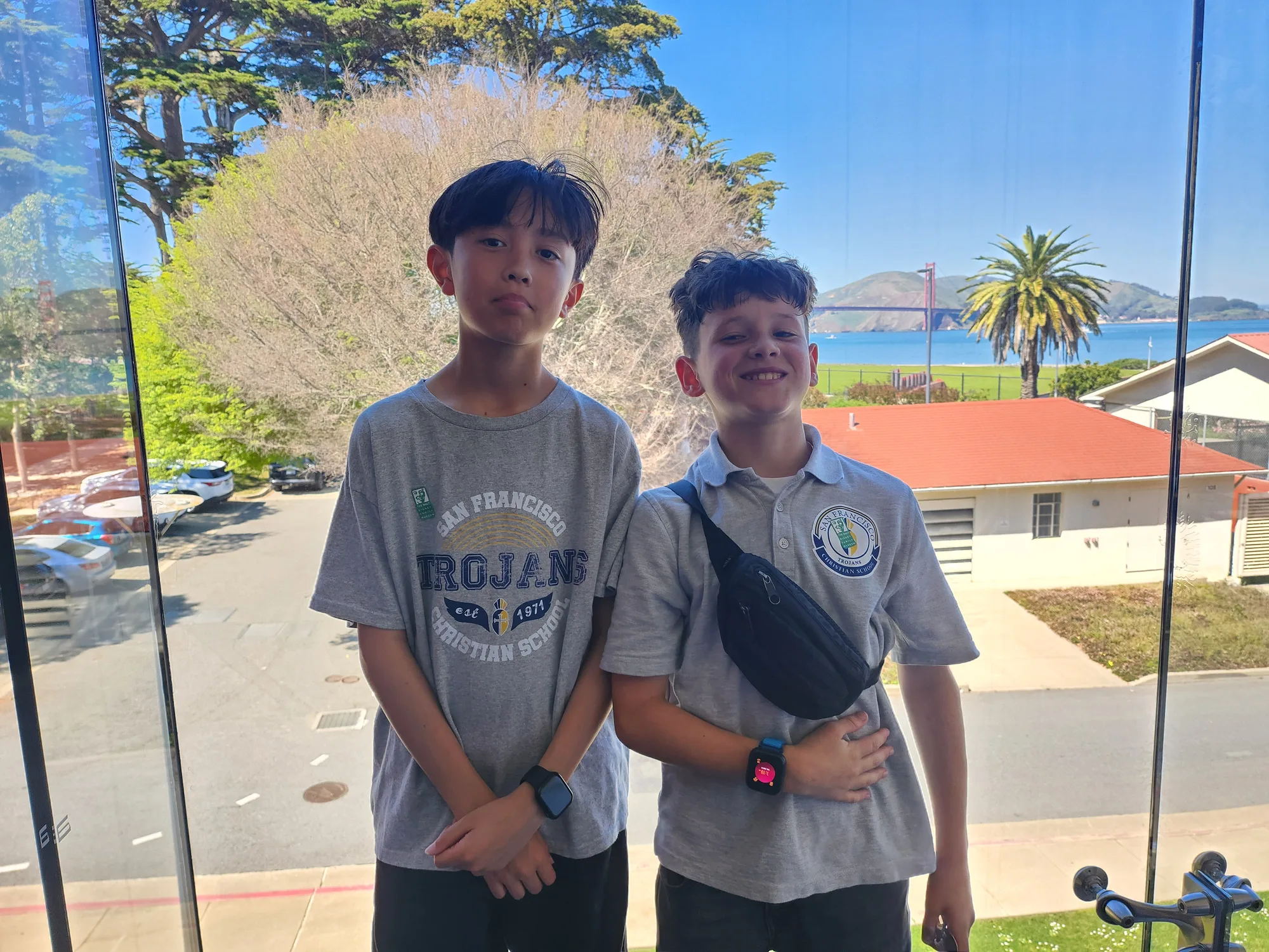 Two students smiling in front of a window framing the Golden Gate Bridge