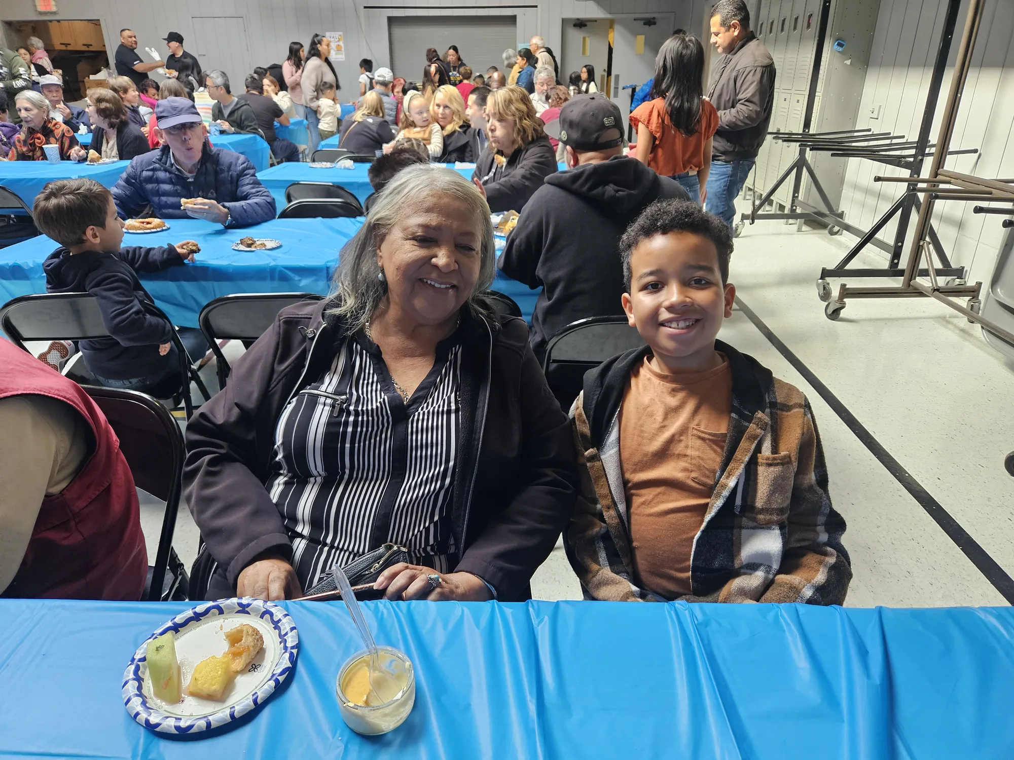 A grandmother and grandson smiling together at a reception table