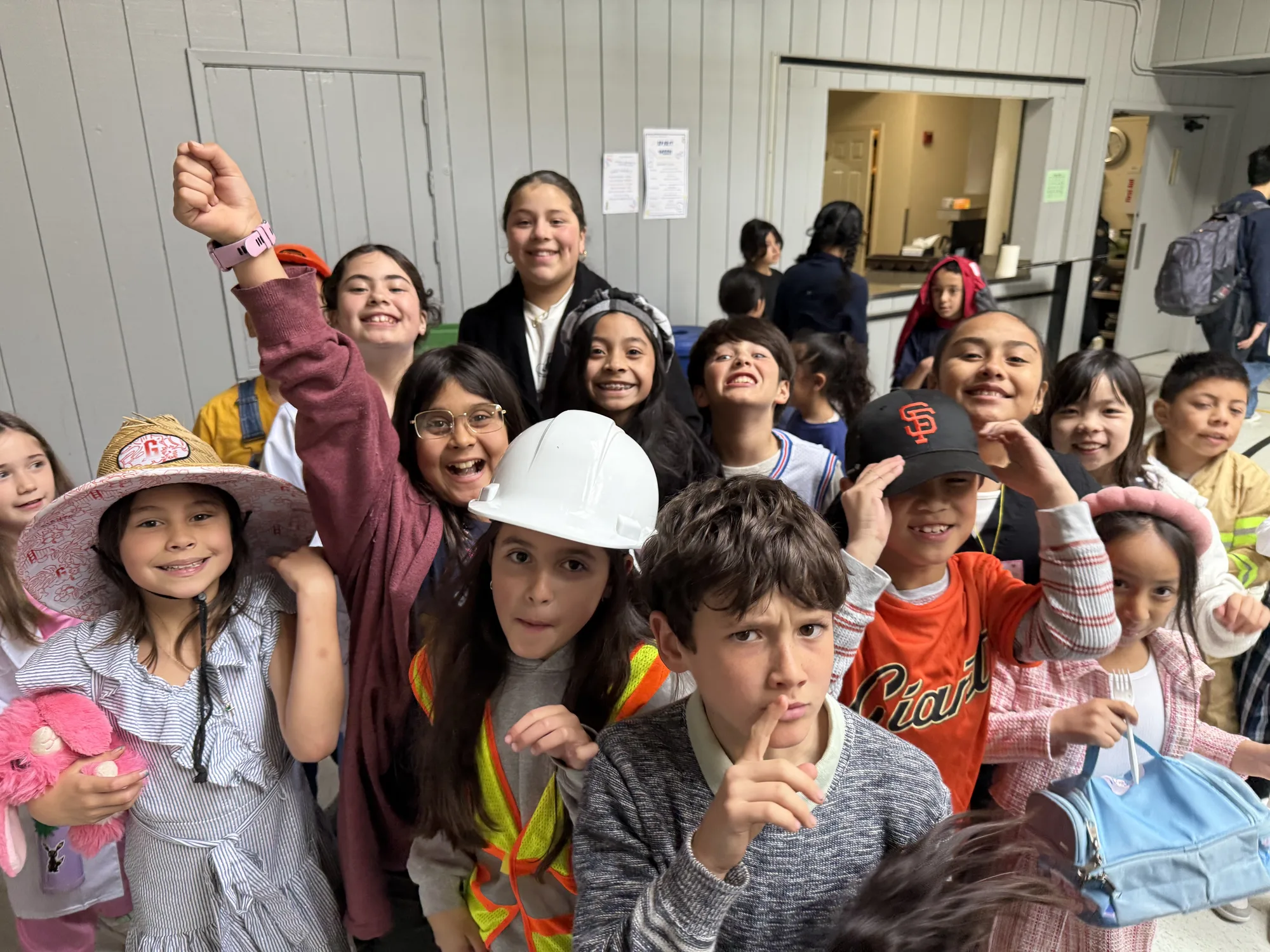 A hallway full of grinning students in community-helper hats on spirit day