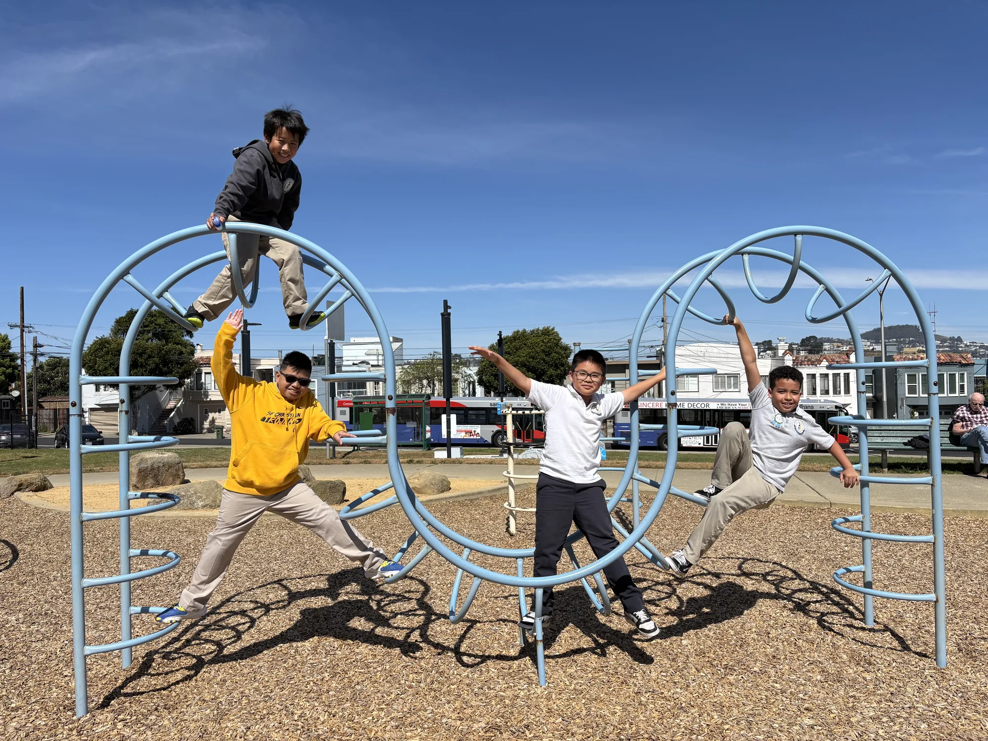 Four boys climbing a playground dome on a sunny day