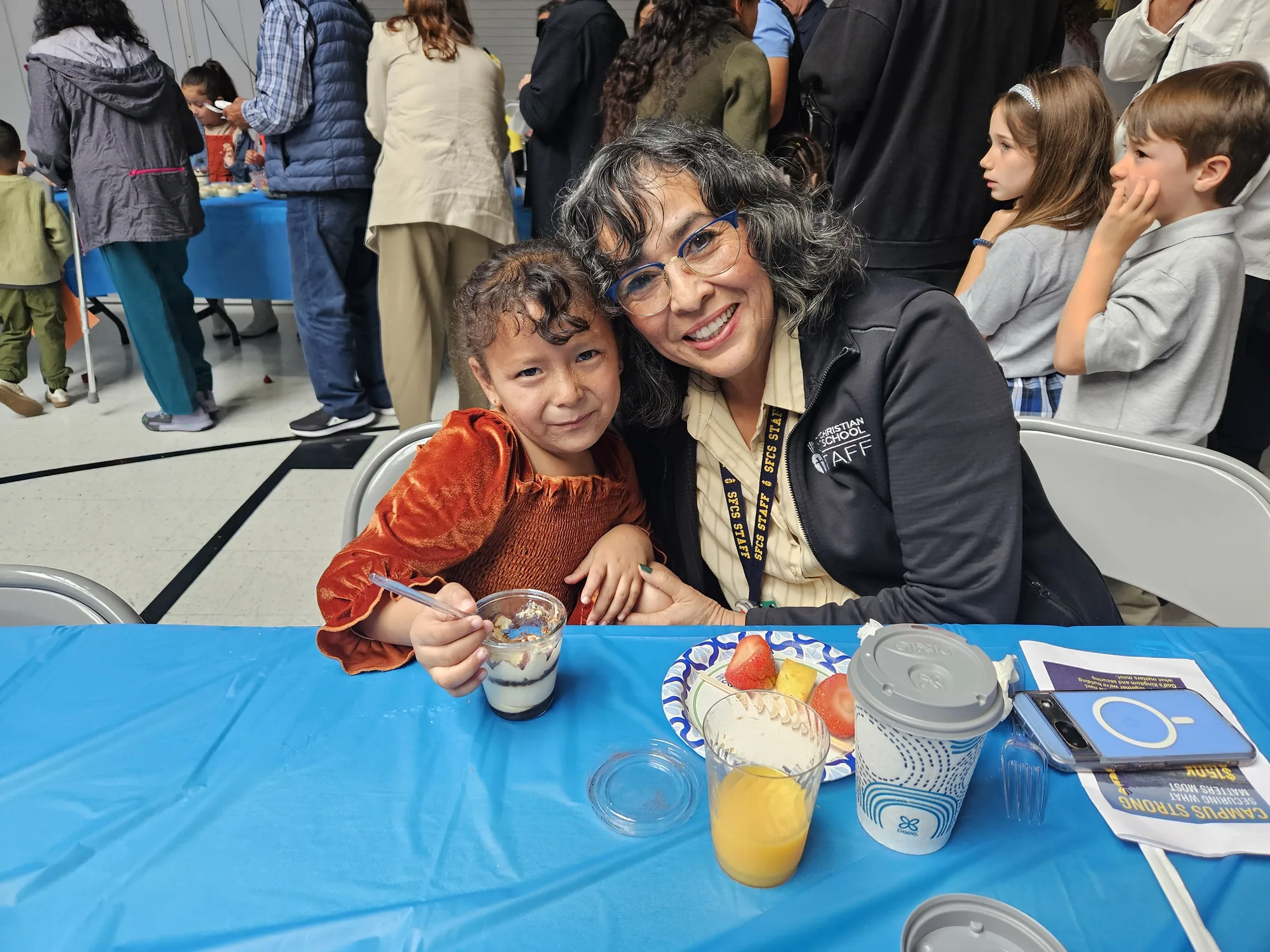 A staff member hugging a young student at the Grandparents Day reception, both beaming