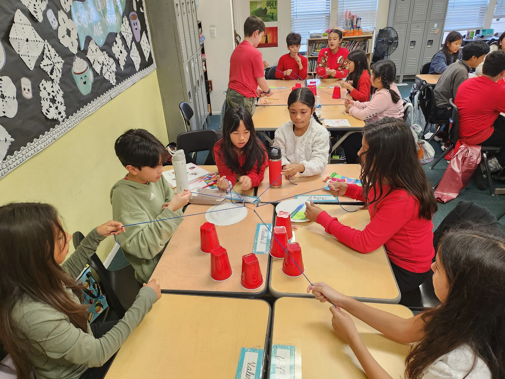 Students threading strings to build a cup tower in a hands-on STEM activity