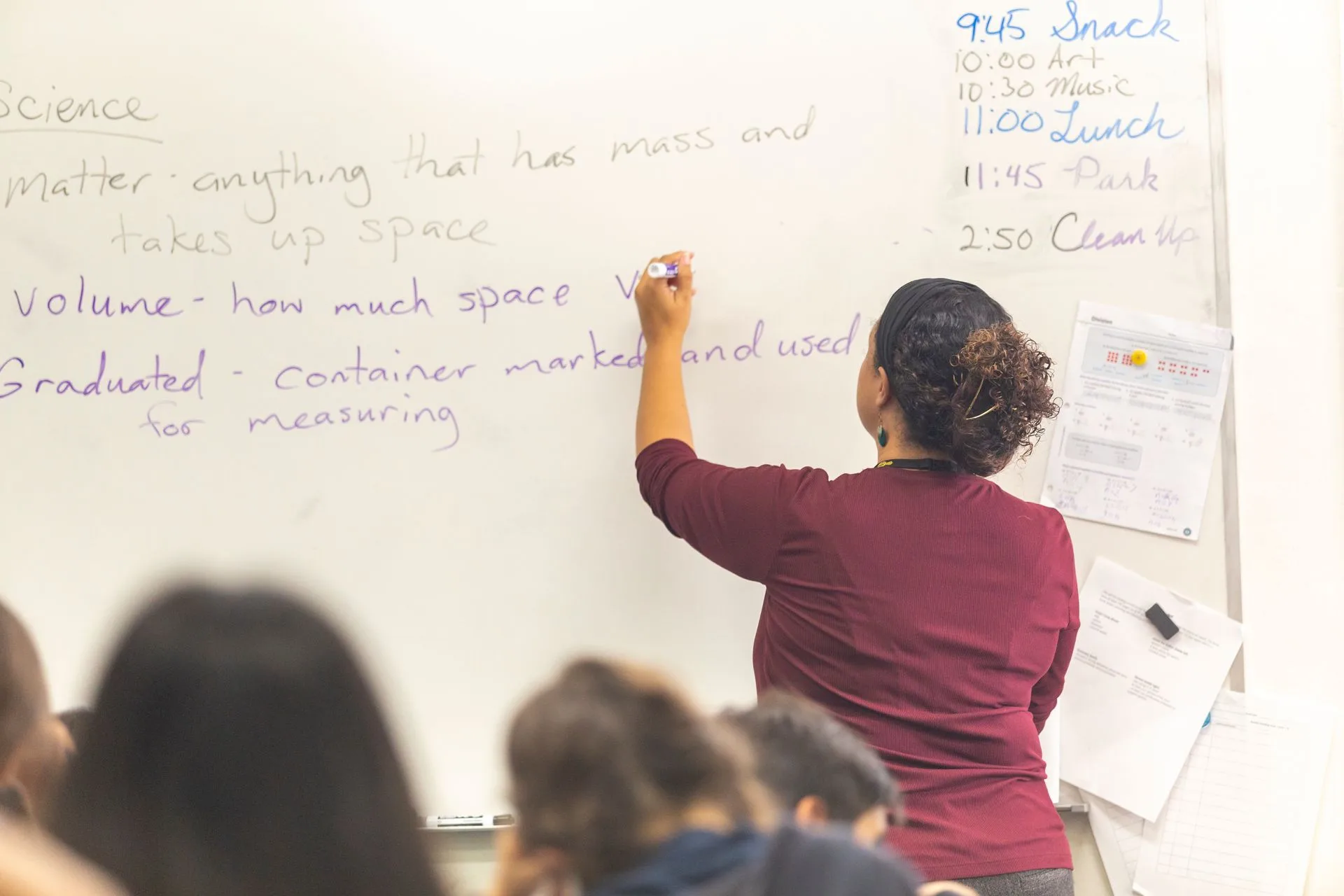 A teacher writing science definitions on the classroom whiteboard