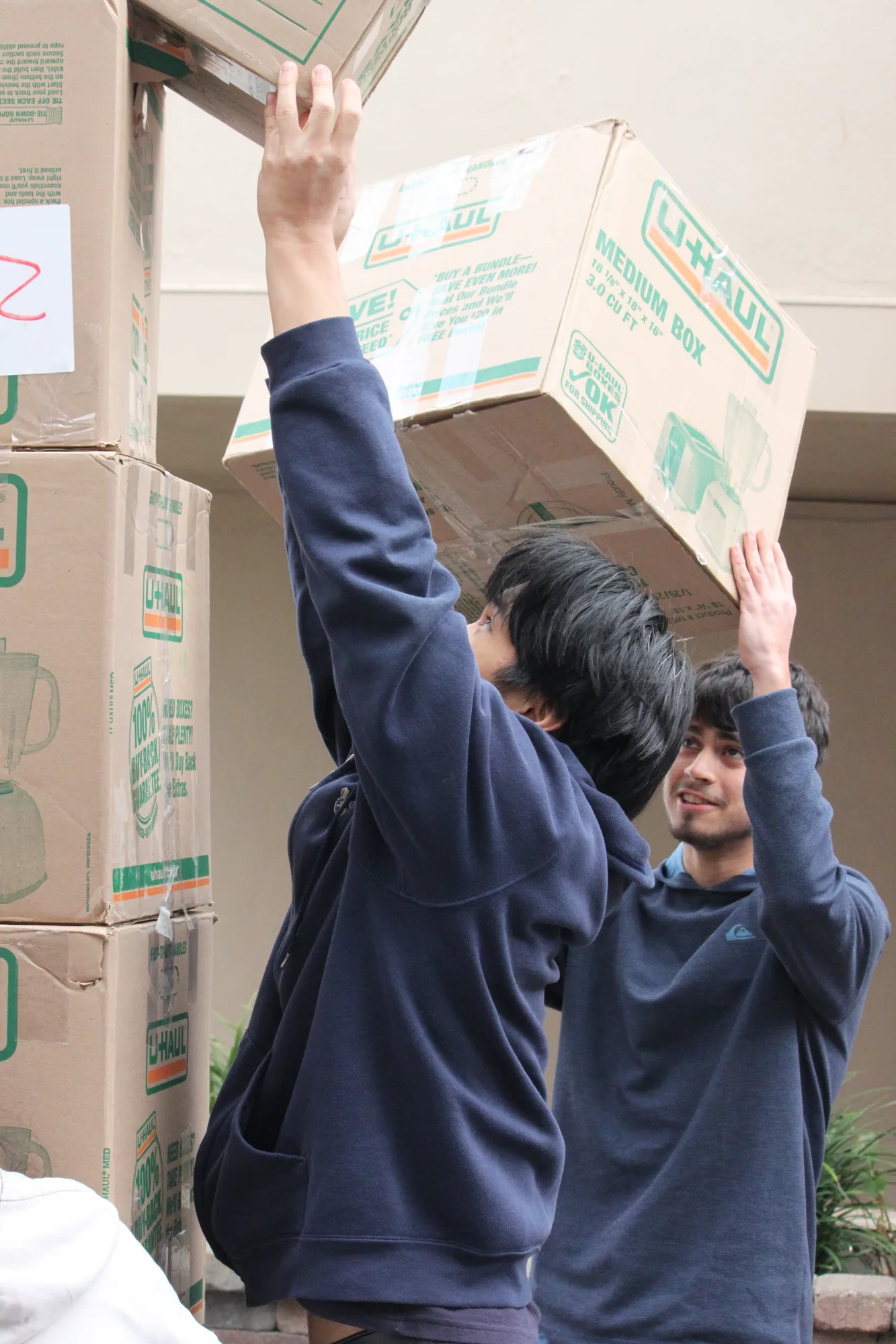 Two students lifting a moving box together during a school service day