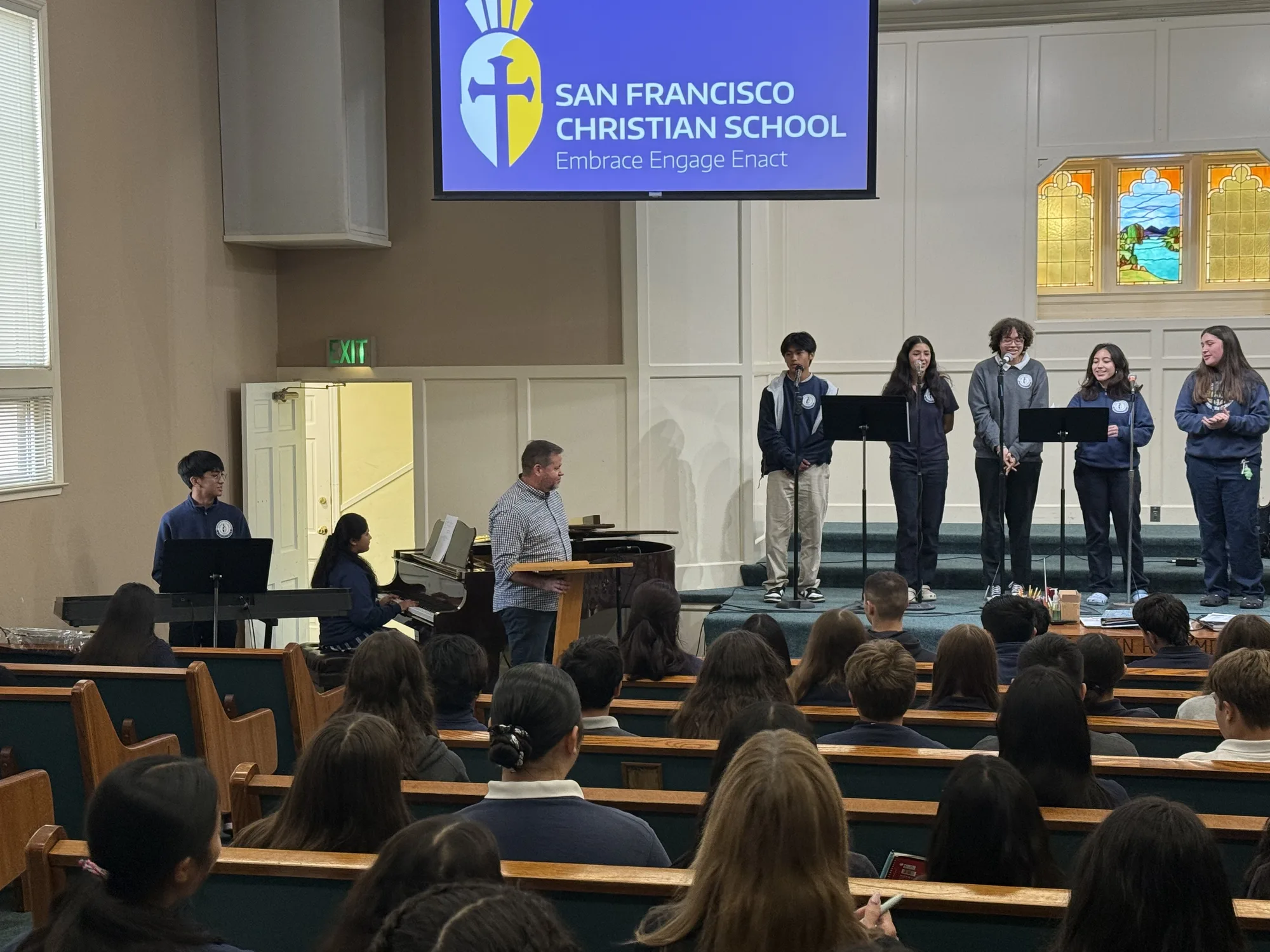 The student worship team leading chapel with the school slide on screen